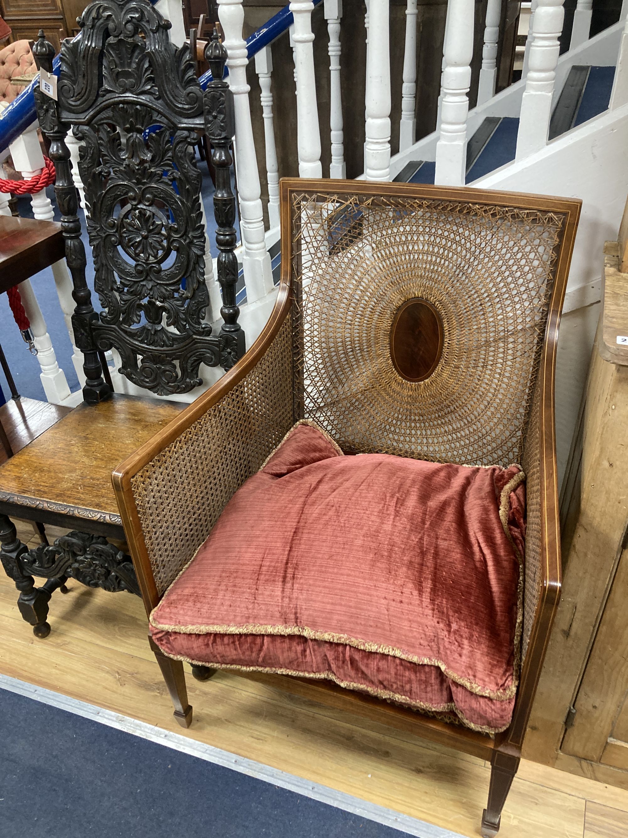 A Flemish carved oak dining chair and an Edwardian bergere chair